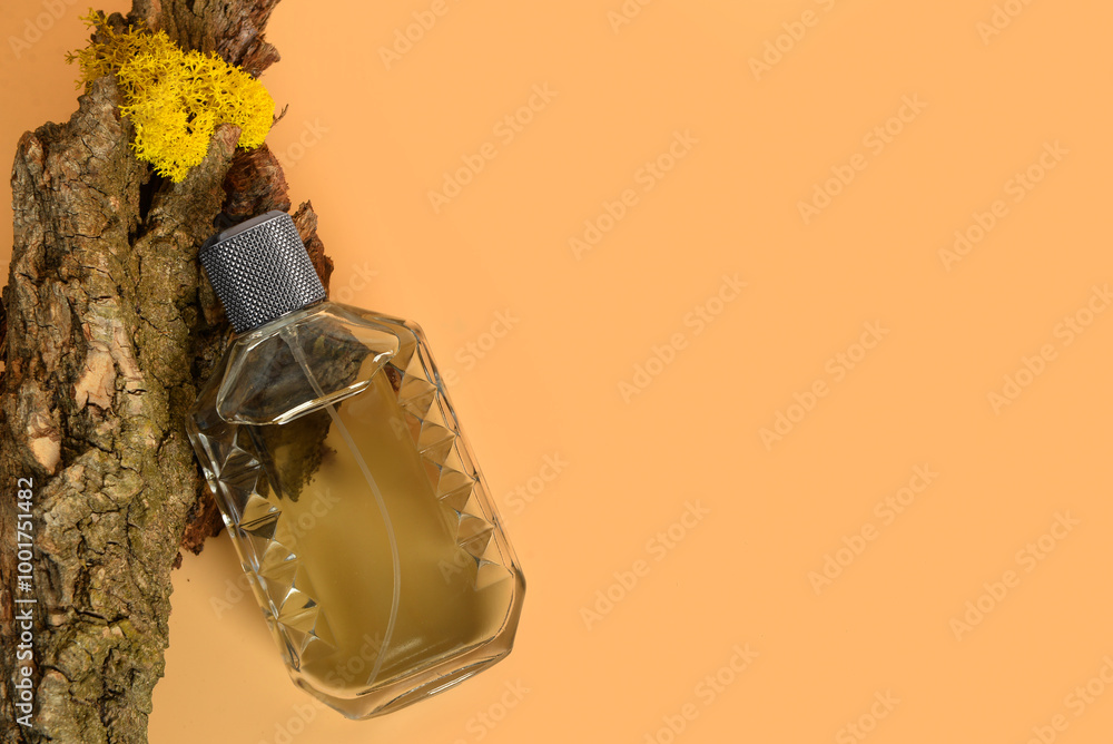 Bottle of perfume and tree bark on orange background