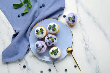 Wall Mural - plate of delicious cupcakes with blueberries and mint on white background