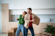© DimaBerlin - Happy couple enjoy on moving day playful dancing with cardboard boxes, smiling in new kitchen. Filled with anticipation for future in new home man, woman celebrate joint purchase apartment in mortgage