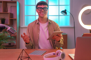 Wall Mural - Young man with tablet computer recording podcast in studio