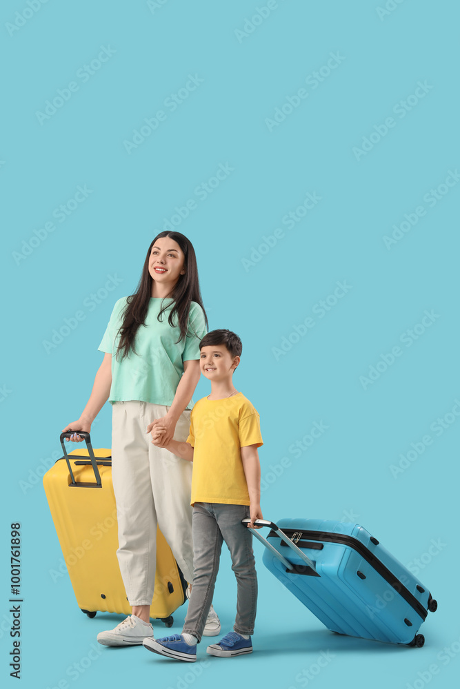 Mother and her little son with suitcases walking on blue background