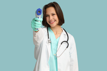 Canvas Print - Beautiful female doctor with infrared thermometer on blue background