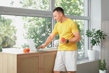 Sticker - Sporty young man with dumbbell using laptop at home