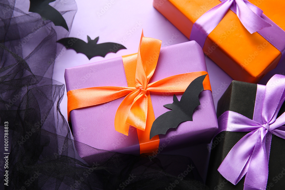 Halloween gifts with bats and tulle on lilac background. Top view