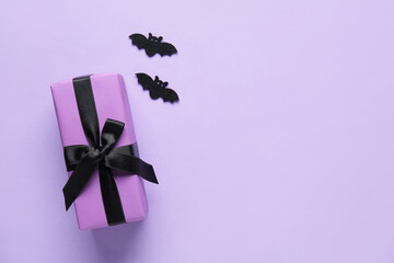 Poster - Halloween gift with paper bats on lilac background. Top view