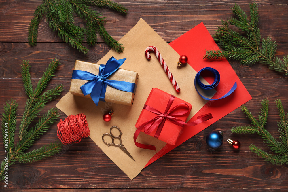 Christmas gift boxes with packing materials, fir branches and decorations on brown wooden background