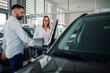 © Zamrznuti tonovi - Man assisting woman in entering modern vehicle at dealership