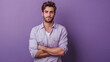 © Filirovska - Young man in a light purple shirt standing against a purple background, arms crossed, looking confidently at the camera with a calm and stylish demeanor