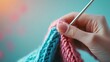 © Naree - A hand holds colorful yarn while crocheting, showcasing a blend of pink and blue threads in a cozy, inviting setting.
