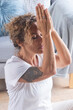 © simona - Tattooed modern woman practicing yoga meditation at home, seeking mental and physical well-being. A serene expression reflects her gratitude for inner peace, living an anti-stress, zen-inspired