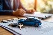 © osagvsa - Car purchase or lease paperwork with keys and a toy car symbolizing a new deal.