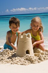 Two happy children building a sandcastle on a sunny beach, enjoying their time by the turquoise ocean.