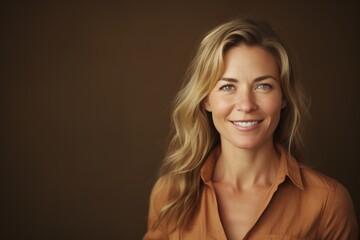 Wall Mural - Portrait of a beautiful blond woman smiling at the camera on a brown background