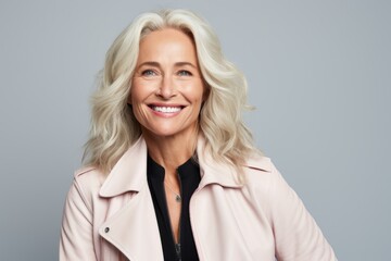 Wall Mural - Portrait of a happy senior businesswoman smiling at camera against grey background