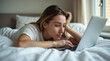 © Daniel L - An attractive woman relaxing in bed while looking at her laptop. Her head is resting on her arm and her fingers are on the keyboard exploring the internet or messaging a friend