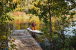 © Aleksey - A Serene Autumn Scene featuring a Paddler gliding across a Calm Lake, beautifully surrounded by Vibrant and colorful Foliage all around