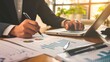 © stock.finder - Businessman working on financial reports at desk with charts and graphs. Office setting with laptop. Close-up photography.
