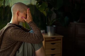 Young female cancer patient with head in hands indoors portrait. Mental health, emotional support, struggles and coping mechanisms during cancer illness.