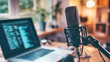 © Anoo - Close-up of a microphone and headphones on an office table near a laptop in a cozy home studio, perfect for podcasting and content creation