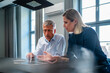© Westend61 - Senior businessman discussing with colleague over tablet PC in office