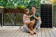 © Westend61 - Father and daughter giving high-five sitting next to solar panel in balcony