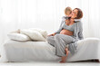 © Westend61 - Happy boy embracing pregnant mother sitting on bed at home