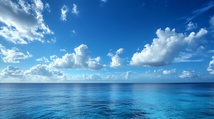 Blue sky with white clouds reflecting in the calm blue ocean water.