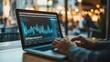 © Penatic Studio - Person Working on a Laptop with a Financial Chart on the Screen