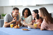 © Antonioguillem - Happy interracial friends checking phone at breakfast in the kitchen