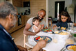 © Maskot - Happy multigenerational family having breakfast on dining table at home