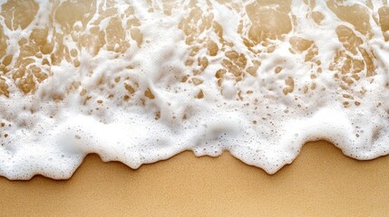 a dynamic top view of waves crashing onto the shore, with frothy white water blending into the smooth, golden sand.