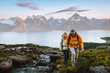 © EVERST - Couple hiking together man and woman climbing mountains exploring Norway healthy lifestyle outdoor active family vacations adventure extreme tour, friends enjoying Lyngen Alps and fjord view