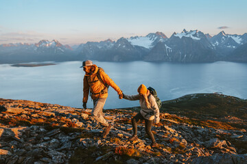 Wall Mural - couple holding hands man and woman hiking in mountains together exploring norway tourists with backp