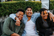 © Maskot - Happy young man with arm around male and female friend enjoying in back yard at social party