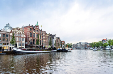 Day view in Amstel, Amsterdam, Netherlands with canal and typical Dutch houses.