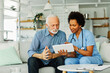 © Lumos sp - nurse doctor senior care tablet computer technology showing caregiver help assistence retirement home nursing elderly woman african american black happy laughing man