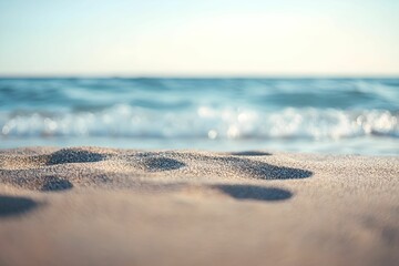 footprints in the sand at sunrise along a peaceful beach near the ocean\'s edge