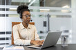 © Liubomir - Confident woman wearing headset using laptop in modern office setting. Focused on customer service with phone support, displaying professionalism and dedication in workplace environment.