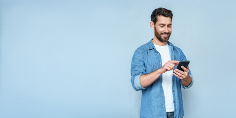 Banner portrait of handsome 30s 40s old businessman using telephone mobile cellphone. Mature smiling freelance man entrepreneur holding smartphone device isolated on blue background with copy space