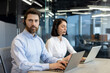 © Liubomir - Two customer service professionals engaged in work at modern office desk. They use laptops and headsets to facilitate effective communication for their roles.