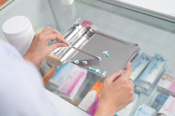 Wall Mural - Asian professional female pharmacist standing with arms crossed looking at camera charming smile pointing hand to pill bottle health care products in pharmacies Close-up and wide-angle shots