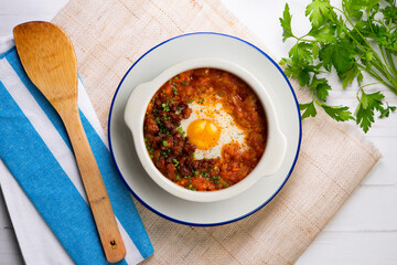 Spanish tapa of baked egg with chorizo ​​and tomato. Top view table with  decorations.