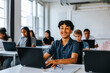 © Maskot - Portrait of smiling curly hair teenage boy sitting with laptop near desk in classroom at school