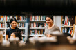© Maskot - Happy female librarian with students in library at school