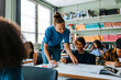 © Maskot - Female teacher helping boy with creativity in drawing class at elementary school