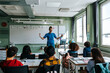 © Maskot - Female professor with arms outstretched teaching group of students in classroom at elementary school