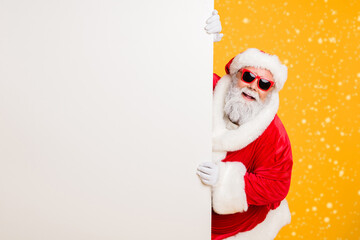 portrait of funny funky christmas father in red hat headwear look behind white wall poster advertise