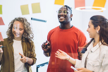 Canvas Print - Smiling colleagues arranging sticky notes on glass wall