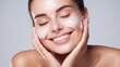 © Iona - Young woman with glowing skin smiles as she lovingly applies face wash, capturing a moment of skincare bliss and radiance.