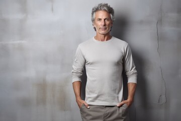 Canvas Print - Portrait of a content man in his 50s showing off a lightweight base layer isolated in bare concrete or plaster wall